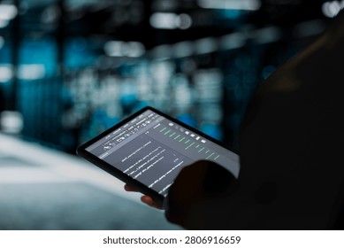 Data center engineer uses a digital tablet in a data center to troubleshoot backend operations and resolve system crashes.