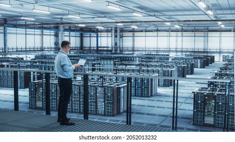 Data Center Engineer Using Laptop Computer. Server Farm Cloud Computing Specialist Facility with Adult Male System Administrator Working with Data Protection Network for Cyber Security.