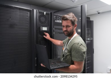 Data Center Engineer Using Laptop Computer Server Room Specialist Facility with Male System Administrator Working with Data Protection Network for Cyber Security or Cryptocurrency Mining Farm. 