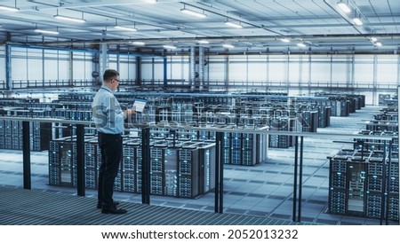 Data Center Engineer Using Laptop Computer. Server Farm Cloud Computing Specialist Facility with Adult Male System Administrator Working with Data Protection Network for Cyber Security.