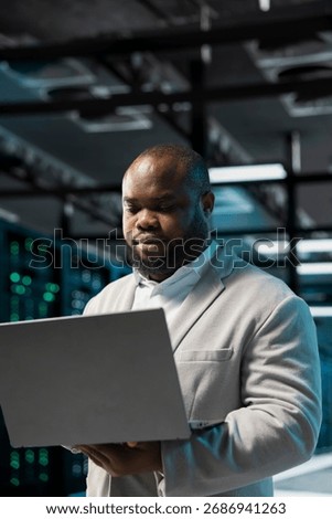 Data center engineer using laptop, monitoring and analyzing metrics to enhance operational effectiveness. Server hub worker utilizing data analytics to predict future infrastructure needs
