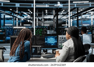 Data center engineering team working together, using AI visualization to oversee automated repetitive tasks. Server farm teamworking colleagues modifying systems based on data analytics graphs