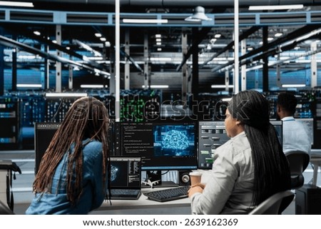 Data center engineering team working together, using AI visualization to oversee automated repetitive tasks. Server farm teamworking colleagues modifying systems based on data analytics graphs