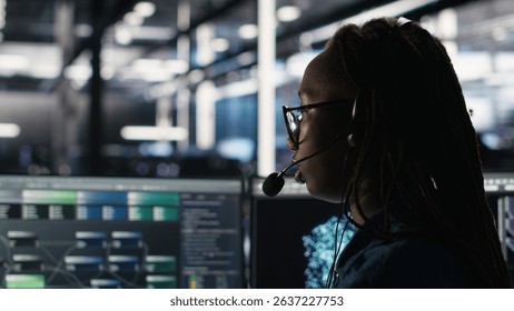 Data center expert examines node tree interface, delivering technical support. Server room technician talking in headset mic with coworkers, using visual programming software, camera B