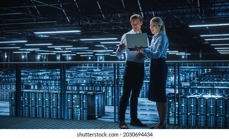 Data Center Female e-Business Enrepreneur and Male IT Specialist talk, Use Laptop. Two Information Technology Engineers work on Bridge Big Cloud Computing Server Farm. - Powered by Shutterstock