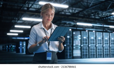 Data Center Female E-Business Entrepreneur Use Tablet Computer With Pleasure Smile. Information Technology Engineer And System Administrator Work In Big Cloud Computing Server Farm.