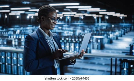 Data Center Female Programmer Using Laptop Computer, Maintenance IT Specialist. In Cloud Computing Server Farm Smiling System Administrator Working On Cyber Security For Iaas, Saas, Paas.