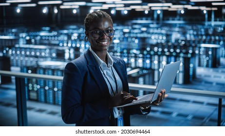 Data Center Female Programmer Using Laptop Computer, Maintenance IT Specialist. In Cloud Computing Server Farm Smiling System Administrator Working On Cyber Security For Iaas, Saas, Paas.