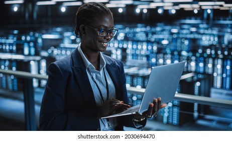 Data Center Female Programmer Using Laptop Computer, Maintenance IT Specialist. In Cloud Computing Server Farm Smiling System Administrator Working On Cyber Security For Iaas, Saas, Paas.