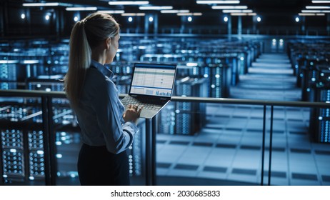 Data Center Female IT Specialist Uses Laptop Computer. Cloud Computing Server Farm with IT Engineer Monitoring Statistic, Maintenance Control. Information Technology of Fintech, e-Business.