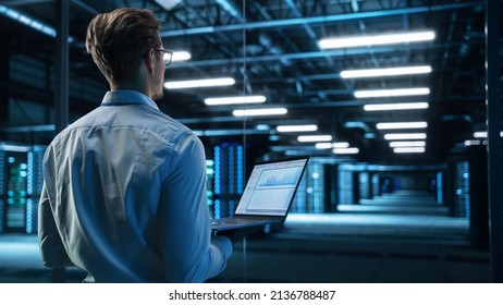 Data Center Male It Specialist Using Laptop while Working on Computer. Information Technology Professional. Server Farm Cloud Computing and Cyber Security Maintenance Concept - Powered by Shutterstock