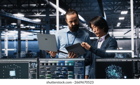 Data center manager supervising developer using device to monitor neural network AI LLMs. Team leader checking progress done by worker overseeing servers powering machine learning processes, camera A