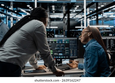 Data center manager supervising work done by engineer using artificial intelligence neural networks. Supervisor overseeing worker in server room using AI programming language to configure hardware