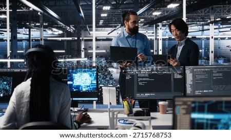 Data center manager supervising work done by programmers working on neural network software. Server hub supervisor overseeing IT staff members implementing deep learning tech, camera A