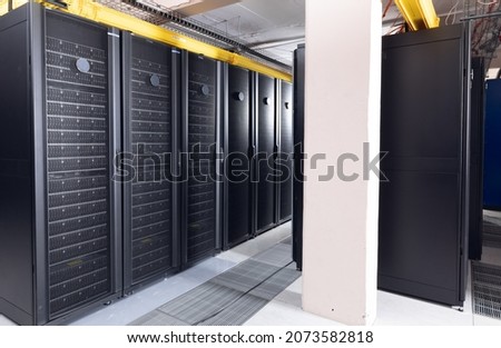 Data center with multiple rows of fully operational server racks. modern cloud computing technology concept.