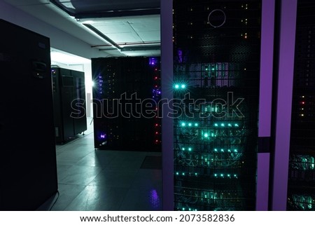 Data center with multiple rows of fully operational server racks. modern cloud computing technology concept.