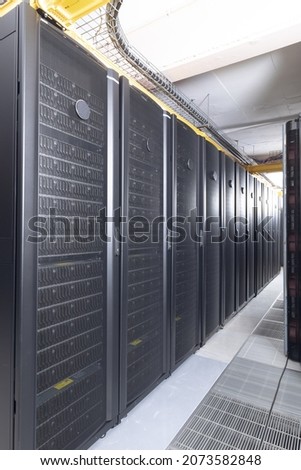 Data center with multiple rows of fully operational server racks. modern cloud computing technology concept.