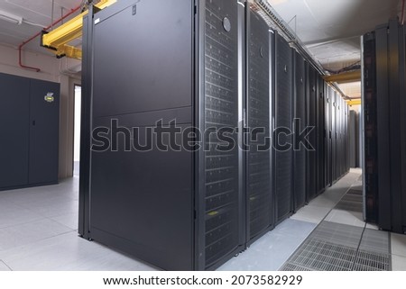 Data center with multiple rows of fully operational server racks. modern cloud computing technology concept.