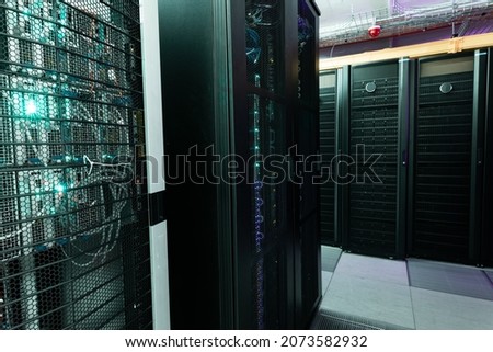 Data center with multiple rows of fully operational server racks. modern cloud computing technology concept.