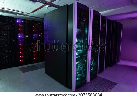 Data center with multiple rows of fully operational server racks. modern cloud computing technology concept.