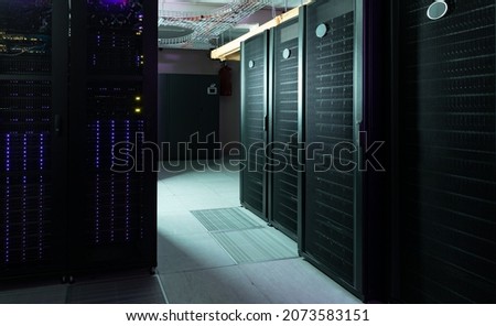 Data center with multiple rows of fully operational server racks. modern cloud computing technology concept.