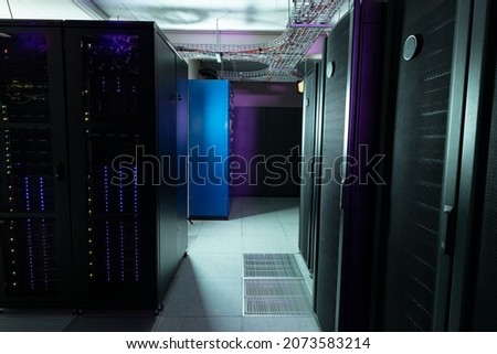 Data center with multiple rows of fully operational server racks. modern cloud computing technology concept.