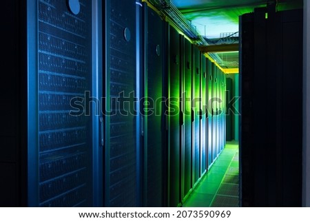 Data center with multiple rows of fully operational server racks. modern cloud computing technology concept.