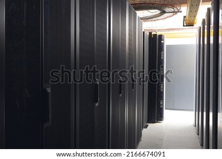 Data center with multiple rows of fully operational server racks. modern cloud computing technology concept.