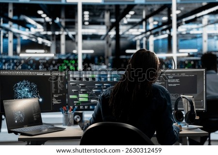 Data center programmer uses AI visual programming technology to oversee automated repetitive tasks. Server room employee modifying infrastructure rigs systems based on data analytics graphs