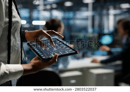 Data center programmer uses a digital tablet in a data center to manage AI systems and optimize server infrastructure.