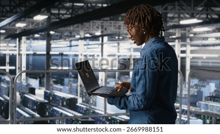 Data center software developer panicking after receiving critical error popup on laptop display. African american woman in server hub alerted by bugs causing low hardware performance