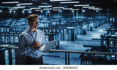 Data Center Specialist Engineer Using Laptop Computer. Server Farm Cloud Computing Facility with Male Maintenance Administrator Working. Data Protection Network for Cyber Security.