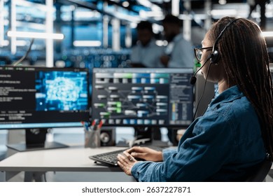 Data center support expert talking in headset microphone, supporting engineering team doing equipment maintenance. Employee in server farm coordinating technicians using mic