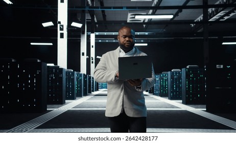 Data center system administrator coding on laptop, doing software updates. Server room IT specialist looking at device screen, optimizing infrastructure rackmounts configuration rigs, camera A