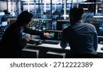 Data center system administrators use PC to monitor neural network using AI LLM. Asian man and colleague at work using artificial intelligence to oversee servers powering machine learning, camera A