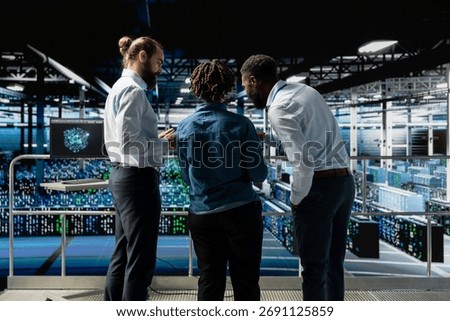 Data center system administrators using laptop to review AI LLM visualization. African american team of engineers use devices to analyze neural network outputs, ensuring stable operations.