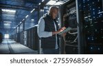 Data center technician inspects server racks, checks network cables, and uses a tablet to monitor hardware status. Rows of illuminated servers, digital infrastructure, and secure network operations.