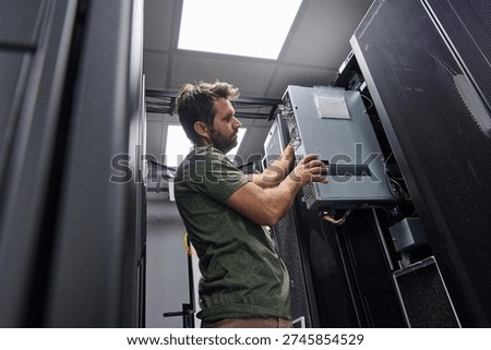 Data center technician installing server hardware and cabling in a server rack during maintenance work