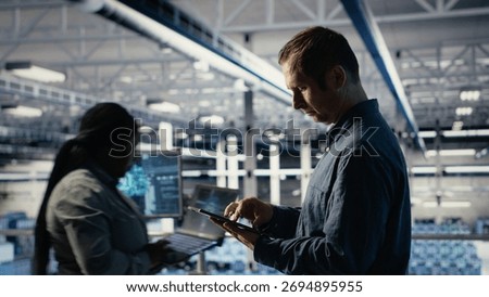 Data center technician monitors machine learning process with tablet, reviewing operational metrics. IT expert using device to review neural networks reports during inspection, camera B