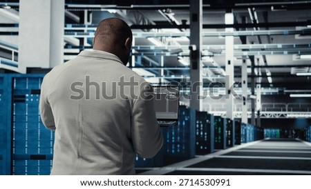 Data center technician using laptop to manage software updates for system stability. African american server room IT professional optimizing performance, configuring infrastructure, camera A