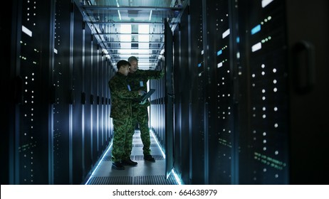 In Data Center Two Military Men Work with Open Server Rack Cabinet. One Holds Military Edition Laptop. - Shutterstock ID 664638979