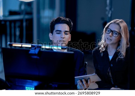 Data deep dive session. Lead analyst points to key metrics on screen comparing dashboard visualization with printed financial report validating findings with team members late night.