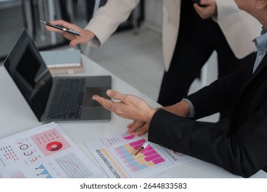 Data Driven Decisions: A team of professionals analyze data on a laptop, collaborating on strategy and insights. They point at charts and graphs, demonstrating their expertise and focus on results