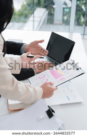 Data Driven Decisions: A team of professionals analyze data on a laptop, collaborating on strategy and insights. They point at charts and graphs, demonstrating their expertise and focus on results