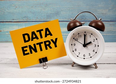 Data Entry text written on paper card with alarm clock on wooden background
