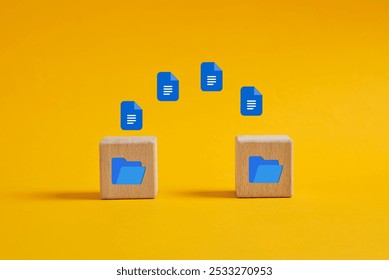 Data or file transfer process between folders. Document icons flying into digital folder on wooden cubes on yellow background.