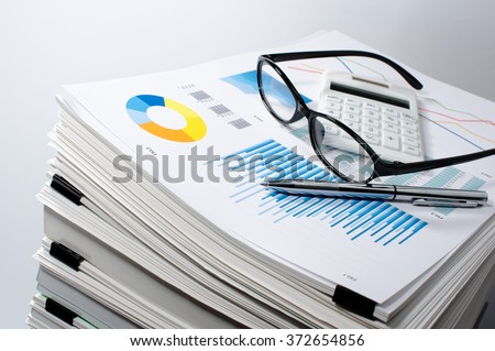 Data management. Document management. Business concept.
Pile of documents on gray background. Graph, glasses, calculate and pen.
