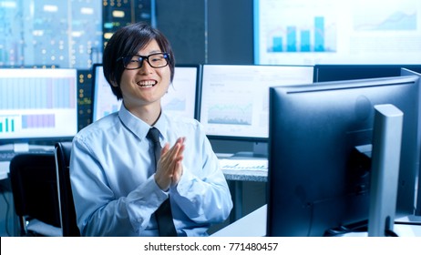 In the Data Mining Center Statistician Claps His Hands while Sitting at His Workstation Surrounded with Monitors Displaying Data and Graphs.