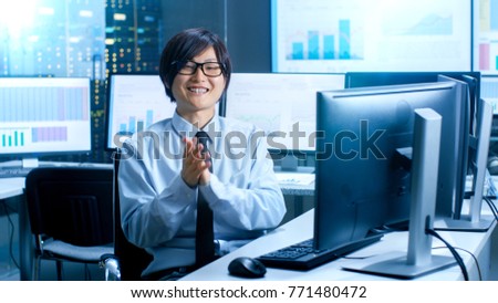 In the Data Mining Center Statistician Claps His Hands while Sitting at His Workstation Surrounded with Monitors Displaying Data and Graphs.