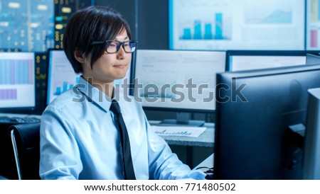 In the Data Mining Center Statistician sits at His Workstation Surrounded with Monitors Displaying Data and Graphs.